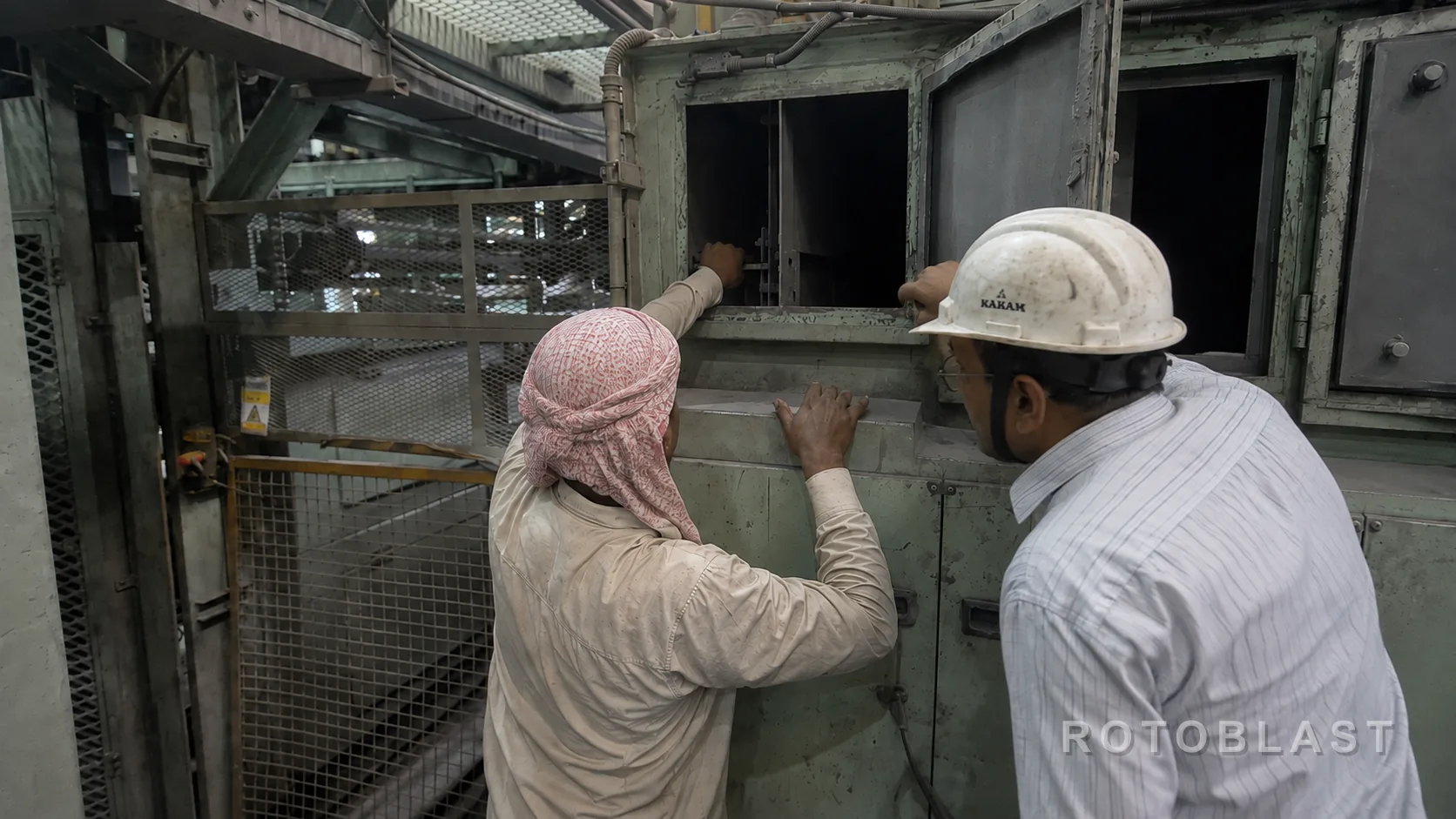 Two Rotoblast engineers inspecting a shot blasting machine's cabinet interior before recommending a replacement part